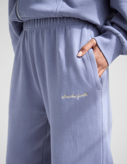 Light blue sweatpants with 'elevated faith' embroidery on a plain background